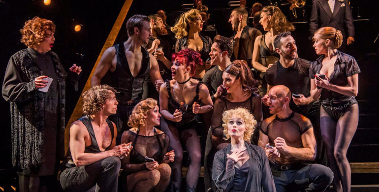 Sarah soetaert (roxie hart) centre seated with the cast of chicago, credit tristram kenton